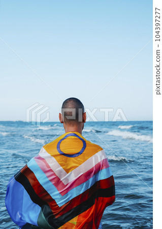 man wrapped in a progress pride flag in the ocean 104397277
