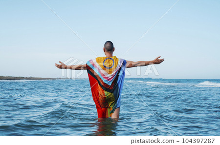 standing in the sea wrapped in a progress pride flag standing in the sea wrapped in a progress pride flag 104397287