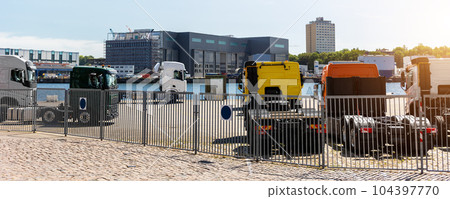 Back view many new heavy commercial cargo transport vehicles stand at port for export import shipping in Germany. Modern semi-trailer business industry truck tractor chassis sale sea logistics 104397770