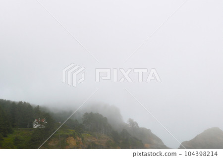 Mountain slopes and forests in fog in the early morning. 104398214