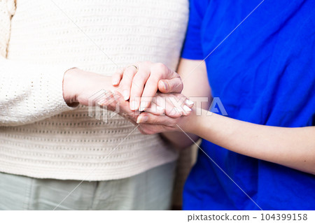 Doctor or nurse shaking hands with a senior woman at home. 104399158