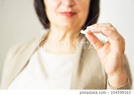 A portrait of a retired woman in casual clothes at home holding her medication.  104399163