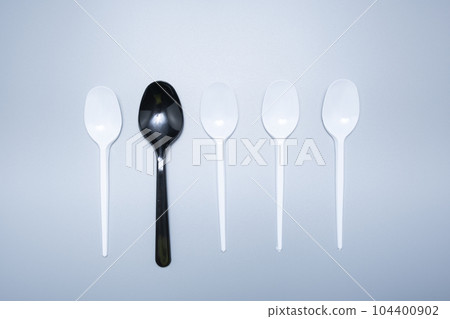 Scattered plastic forks knives spoons on a gray background close-up Scattered plastic forks knives spoons on a gray background close-up 104400902