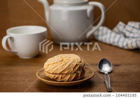 Scene of tea time with small delicious homemade round cake filled with blueberry cream in wooden dish. 104403185