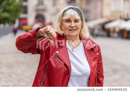 Upset senior woman showing thumbs down sign, disapproval, dissatisfied bad work, mistake in city Upset senior woman showing thumbs down sign, disapproval, dissatisfied bad work, mistake in city 104404638