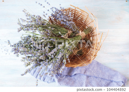 Bouquets of lavender flowers in a wicker basket on a wooden table, top view 104404892