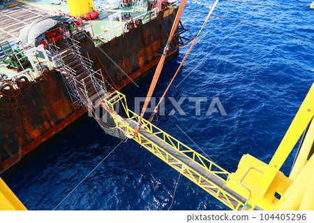 Gangway from supply boat or barge to the oil and gas platform. The activity supported man power to work on the platform. Oil and gas construction activities and support service job. Gangway from supply boat or barge to the oil and gas platform. The activity supported man power to work on the platform. Oil and gas construction activities and support service job. 104405296