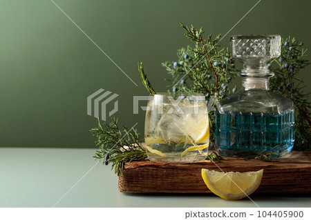 Cocktail gin-tonic with ice, lemon, and rosemary in a frozen glass. Cocktail gin-tonic with ice, lemon, and rosemary in a frozen glass. 104405900