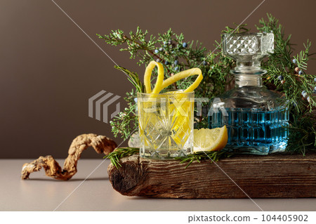 Cocktail gin-tonic with ice, lemon, and rosemary in a frozen glass. 104405902