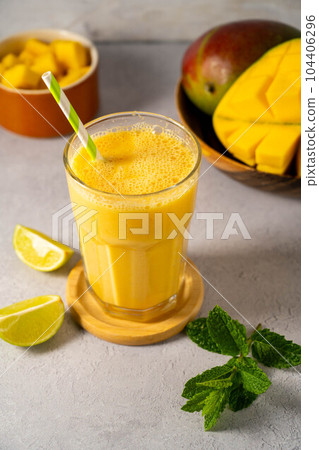 Mango smoothie in a glass with fresh mango, mint and lime. 104406296