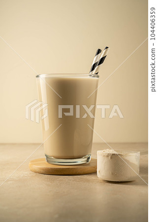 Protein powder in a scoop and a glass of protein drink. Bodybuilding, fitness sport, health and nutrition. Protein powder in a scoop and a glass of protein drink. Bodybuilding, fitness sport, health and nutrition. 104406359