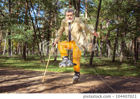 Funny old man on roller skates and walking stick. 104407021