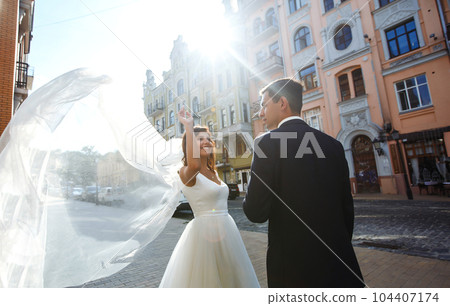Bride and groom kisses tenderly in the shadow of a flying veil. Together. Wedding. Love. 104407174