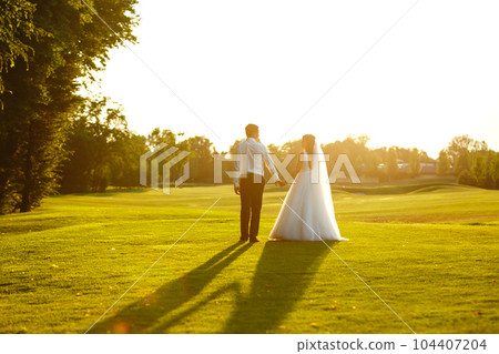 Happy bride and groom go into the sunset. Lovely wedding couple at sunset. Together. Wedding. Happy bride and groom go into the sunset. Lovely wedding couple at sunset. Together. Wedding. 104407204