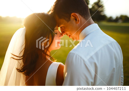 Lovely wedding couple at sunset. Bride, groom in wedding attire with bouquet of flowers. Romantic. Lovely wedding couple at sunset. Bride, groom in wedding attire with bouquet of flowers. Romantic. 104407211