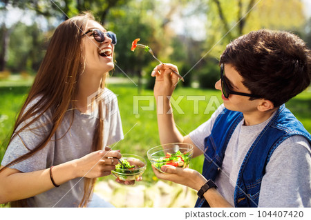 friends enjoying a healthy meal. Boy and girl eating healthy food. Healthy lifestyle. Concept picnic. 104407420