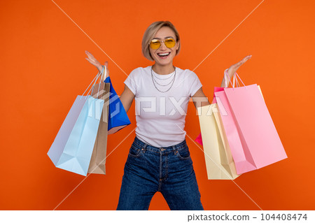 Extremely happy woman in white t shirt and jeans standing with shopping bags Extremely happy woman in white t shirt and jeans standing with shopping bags 104408474