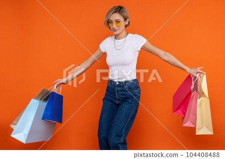 Festive woman in white t shirt and jeans holding bags enjoying shopping 104408488