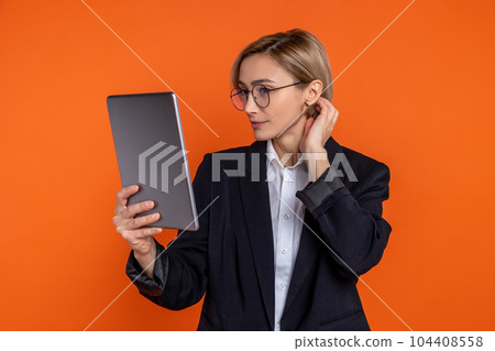 Attractive woman wearing black official style suit standing with tablet 104408558