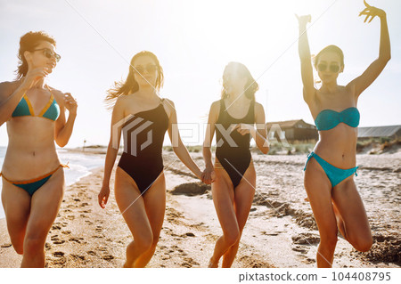 Four young girls having fun on the beach. Group of girlfriends enjoying on beach holiday. Summer lifestyle. Four young girls having fun on the beach. Group of girlfriends enjoying on beach holiday. Summer lifestyle. 104408795