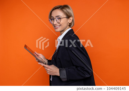 Profile portrait of happy woman wearing black official style suit working online on tablet Profile portrait of happy woman wearing black official style suit working online on tablet 104409145