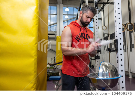 Man clapping hands preparing for workout at gym using chalk for plams before training. 104409176
