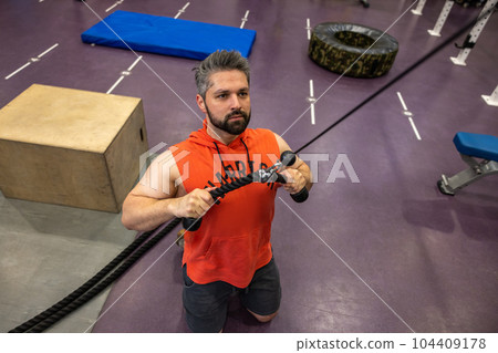 Strong sporty man training triceps and biceps at gym, doing cable rope pushdowns. Strong sporty man training triceps and biceps at gym, doing cable rope pushdowns. 104409178