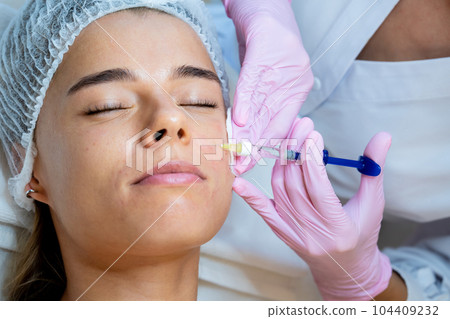 PRP ttherapy in beauty clinic, cosmetologist doing injections to woman's face to cure problem skin. 104409232