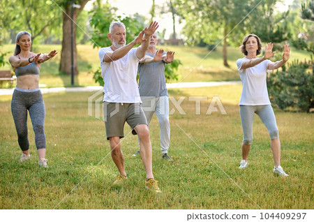 A group of people practicing qigong in a park 104409297