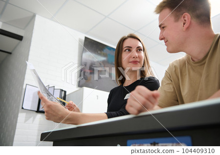 Concept of healthy care and medicine. Beautiful nurse woman have a discussion with the patient good looking man, they discussing beside the reception counter in modern clinic or outpatient patient 104409310
