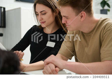 Caucasian handsome young man patient in medical clinic, asking the doctor dentist informations while filling in stomatological form, standing by reception desk in dentistry clinic. Healthcare Medicine 104409311
