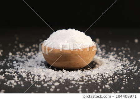 salt into a wooden spoon from a bowl on a black salt into a wooden spoon from a bowl on a black 104409971