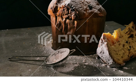 Christmas baking in Italy. Delicious festive bread with powdered sugar. View on black background. Christmas baking in Italy. Delicious festive bread with powdered sugar. View on black background. 104410344