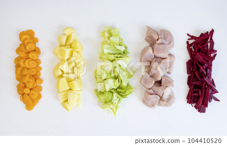 Sliced colored vegetables and meat on a white background. The concept of cooking. 104410520