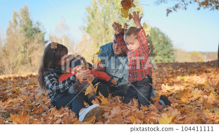 A happy family in an autumn park having fun and crumbling leaves. A happy family in an autumn park having fun and crumbling leaves. 104411111
