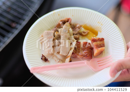 A scene where the meat grilled on the barbecue is served on a plate A scene where the meat grilled on the barbecue is served on a plate 104411529