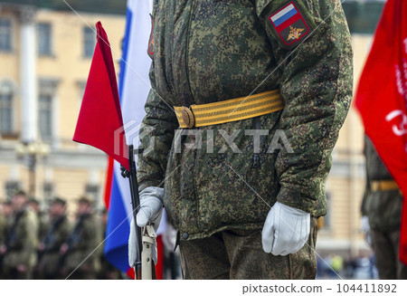 Field military uniform of Russian soldier at parade rehearsal against the background of the colors of the national flag. Field military uniform of Russian soldier at parade rehearsal against the background of the colors of the national flag. 104411892