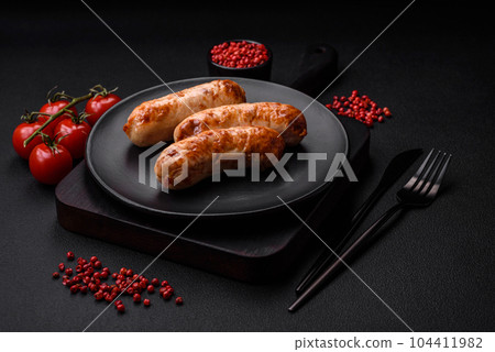 Delicious juicy grilled sausages with salt, spices and herbs on a ceramic plate Delicious juicy grilled sausages with salt, spices and herbs on a ceramic plate 104411982