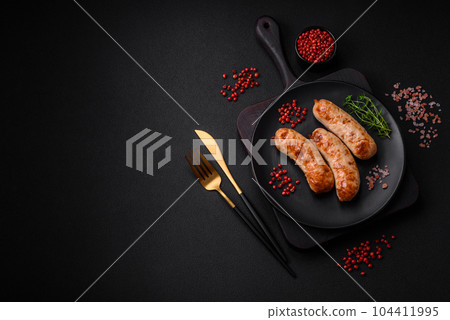 Delicious juicy grilled sausages with salt, spices and herbs on a ceramic plate Delicious juicy grilled sausages with salt, spices and herbs on a ceramic plate 104411995