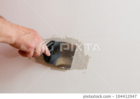 A handyman is repairing a hole in the drywall in the wall. A handyman is repairing a hole in the drywall in the wall. 104412047