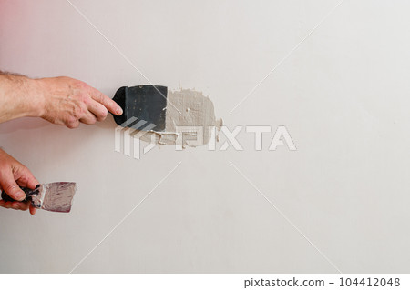 A handyman is repairing a hole in the drywall in the wall. A handyman is repairing a hole in the drywall in the wall. 104412048