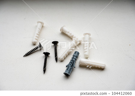 Screws and plastic dowels on a white background. 104412060