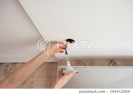 Hand inserts the lamp into the ceiling Hand inserts the lamp into the ceiling 104412069