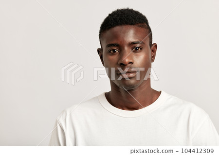 Young handsome confident African guy displaying the results of consistent skincare and grooming routine in a studio. A black man caring for the skin to maintain his youthful and healthy appearance. Young handsome confident African guy displaying the results of consistent skincare and grooming routine in a studio. A black man caring for the skin to maintain his youthful and healthy appearance. 104412309