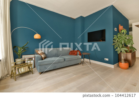 a living room with blue walls and white trim on the walls there is a grey couch in front of it a living room with blue walls and white trim on the walls there is a grey couch in front of it 104412617