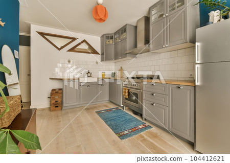 a kitchen with blue walls and wood flooring in the middle part of the room, there is a plant on the right side 104412621