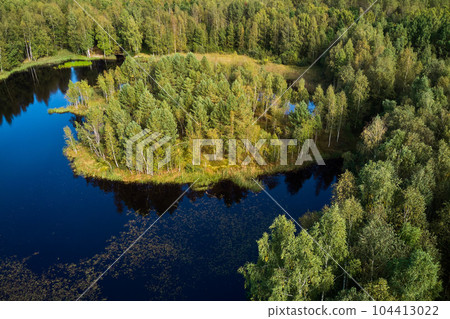 Aerial view of a picturesque landscape with a peat lake and a small island surrounded by green forest Aerial view of a picturesque landscape with a peat lake and a small island surrounded by green forest 104413022