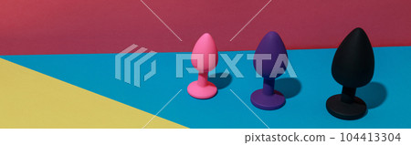 Different buttplugs and dildos for anal sex on colored background with shadows. Sex shop concept Different buttplugs and dildos for anal sex on colored background with shadows. Sex shop concept 104413304