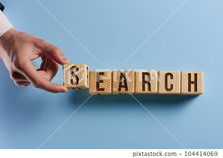 Magnifier and search word written on cube over wooden background 104414069