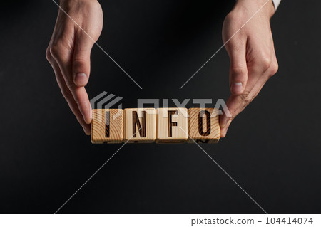 hand examines the words INFO through a magnifying glass on a bla 104414074